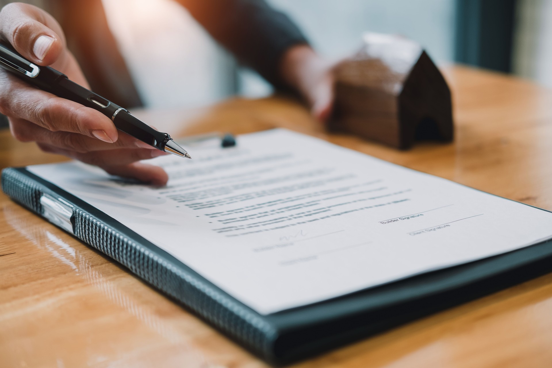 Signing contract. Close-up of confident young man signing some document while another man in shirt and tie sitting close to him and pointing document